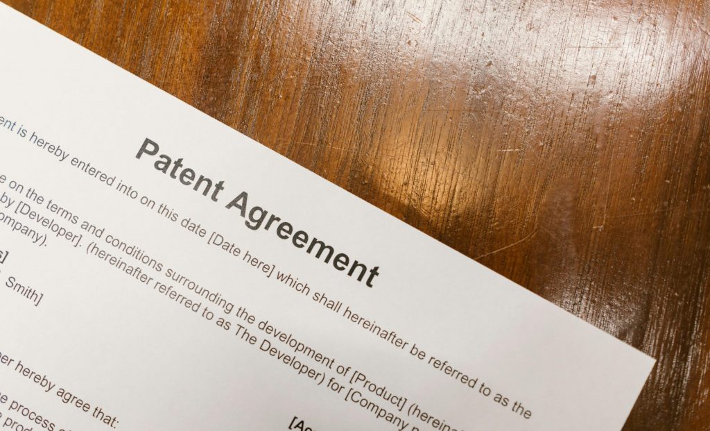 Patent Support Services 04 Detailed close-up of a patent agreement document on a polished wooden table.