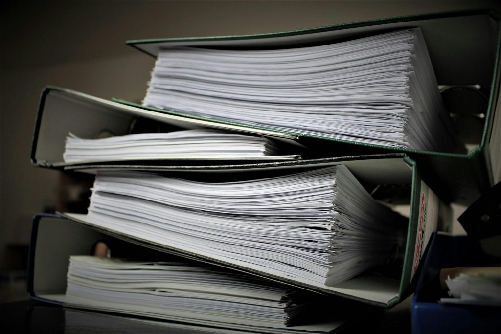 Regulatory Submission Services 03 Close-up of stacked binders filled with documents for office or educational use.